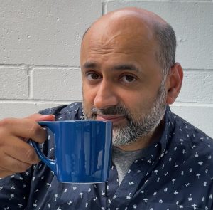 Image of Navneet holding up a coffee cup